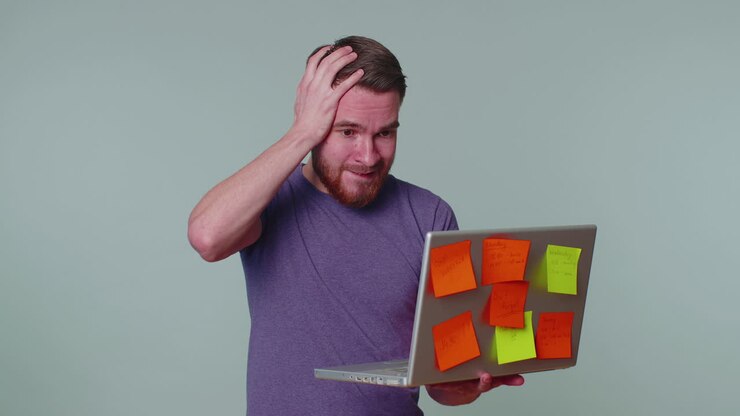Freelancer esausto con post-it, che utilizza il laptop, con problemi di concentrazione
