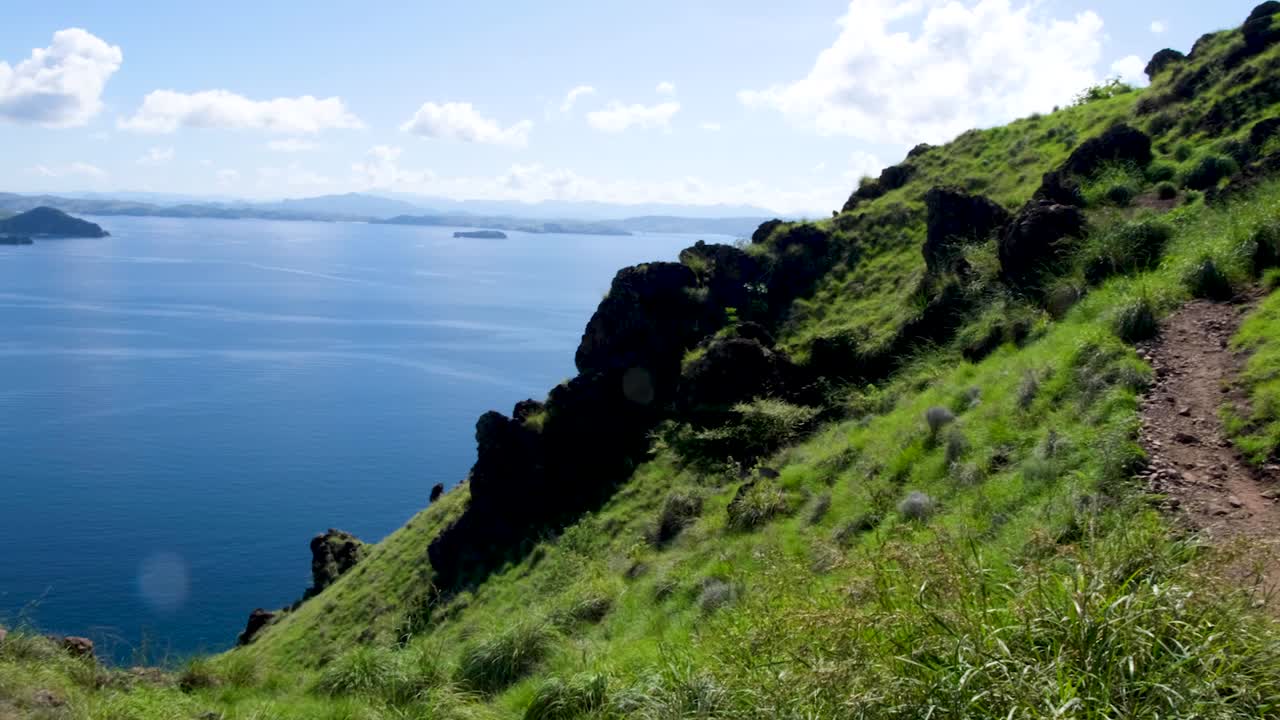 empinadas laderas cubiertas de hierba verde de una isla tropical rocosa y escarpada con vistas al océano en el este de nusa tenggara, indonesia
