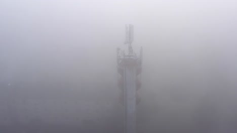 telecommunication broadcasting antennas in a fog on water tower, aerial orbital view