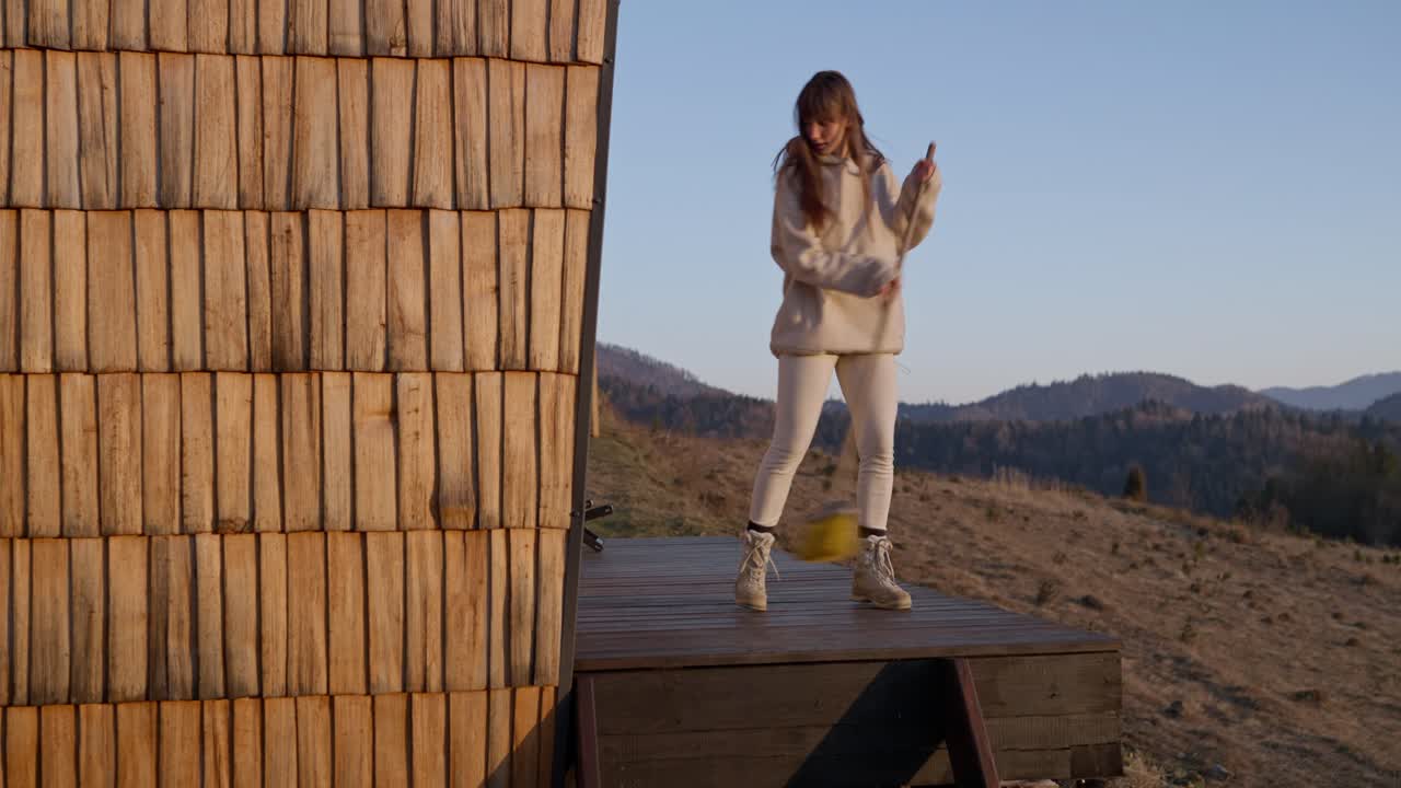 Woman sweeping the deck of a cabin in the mountains