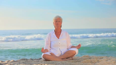 mujer madura de blanco haciendo yoga