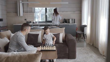 father and son playing chess at home