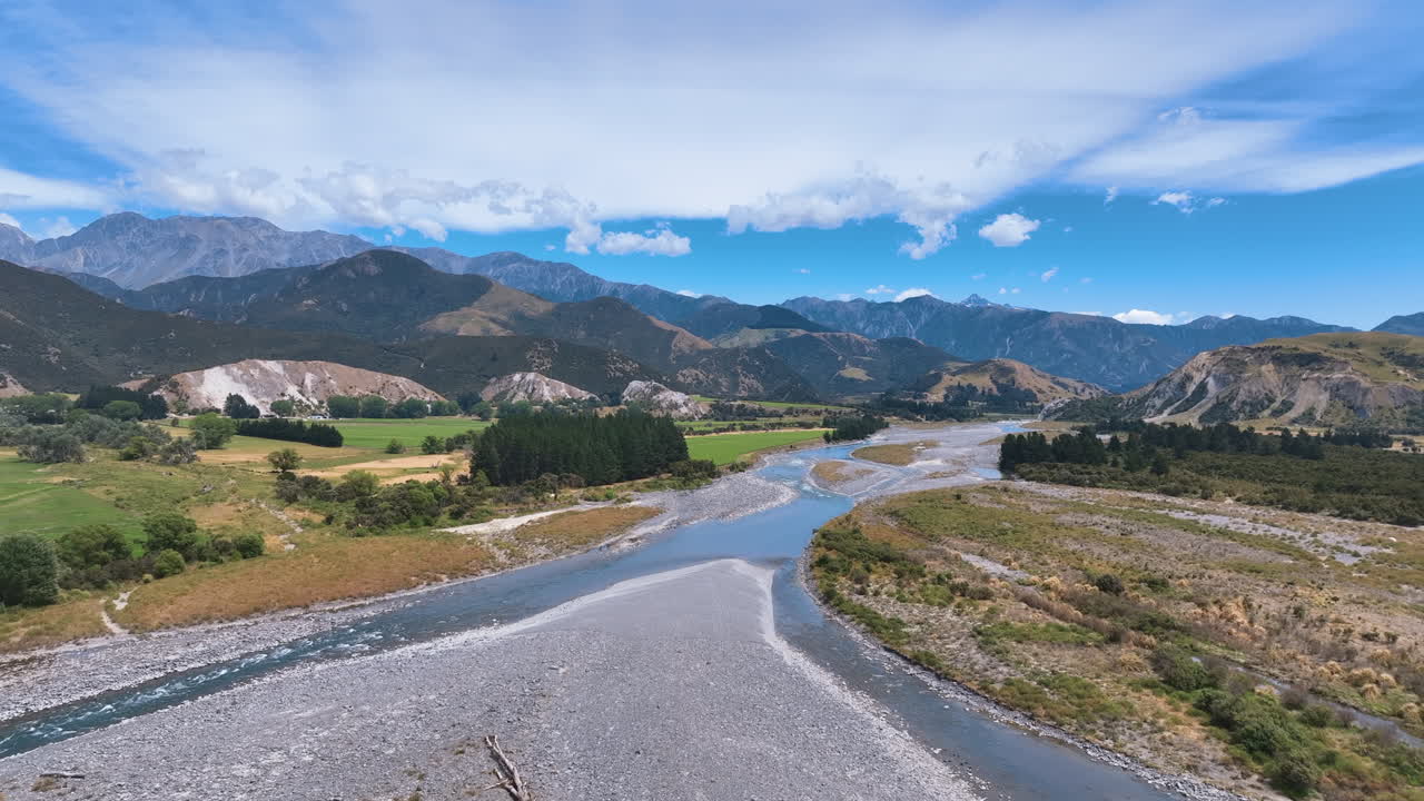 Aerial flies across the broad braided Buller River as it forks into two channels amongst wide valley and vast mountain backdrops, West Coast, Westport, Buller Gorge Aotearoa New Zealand