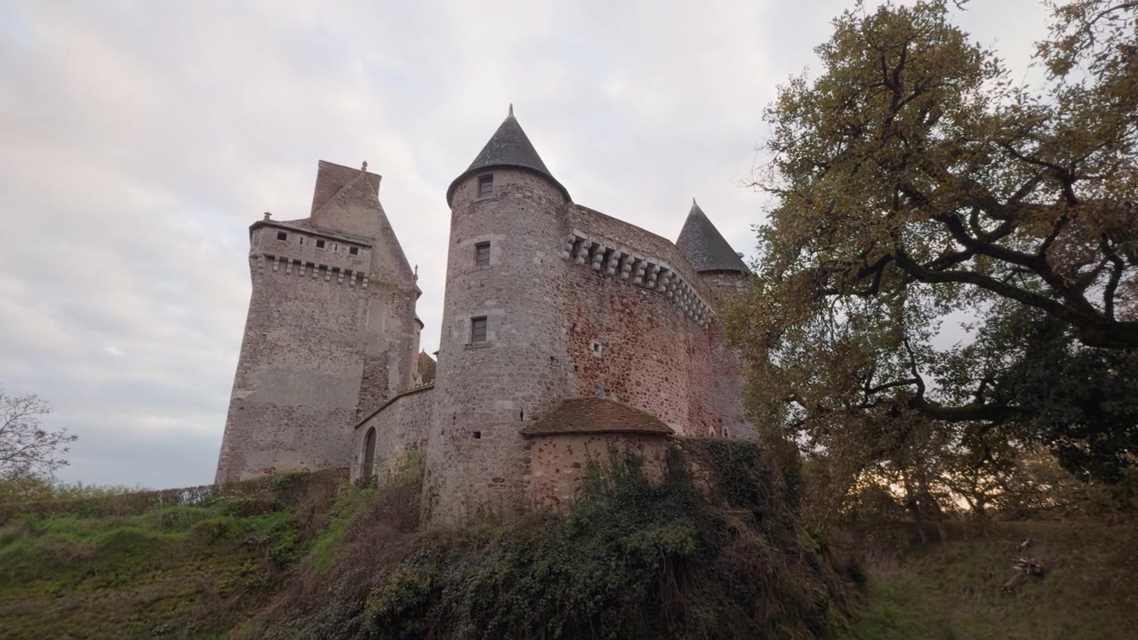 Historyczny zamek Château du Bouchet w Rosnay we Francji, otoczony naturą pod delikatnym, zachmurzonym niebem