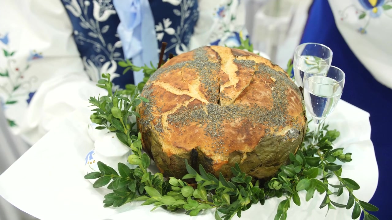 Donna polacca in abiti tradizionali regge un vassoio di benvenuto personalizzato con pane, sale e acqua a un matrimonio