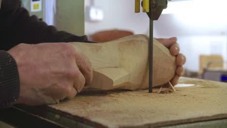 bespoke shoemaker shaping wooden last for shoe using jigsaw