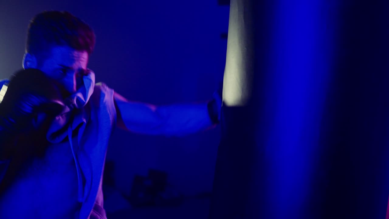 Uomo che si allena a boxe in una palestra al neon