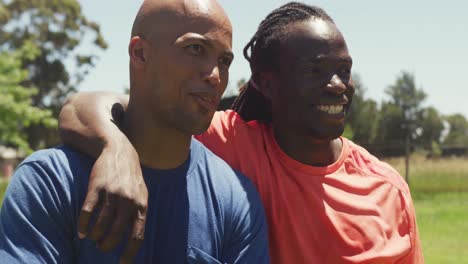 two happy african american men smiling and embracing in sun after completing obstacle course