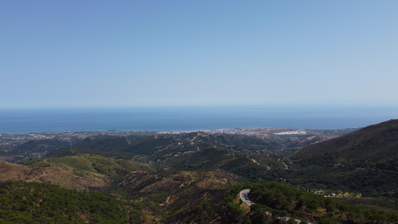 Paesaggio montuoso della costa spagnola con l'oceano blu all'orizzonte, vista aerea.