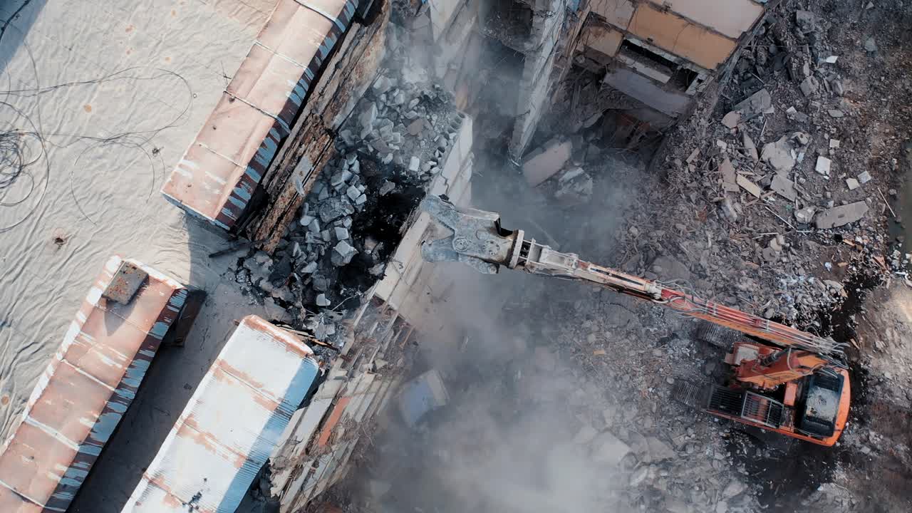 Aerial View Excavators Dismantle The Concrete Structures Of The Building. Hydraulic machinery working to get rid of the rubbish in a demolition site