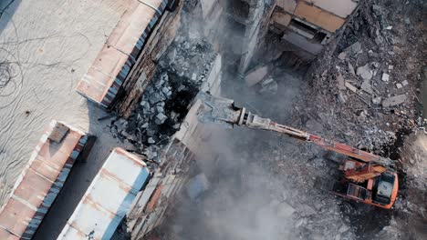 aerial view excavators dismantle the concrete structures of the building. hydraulic machinery working to get rid of the rubbish in a demolition site