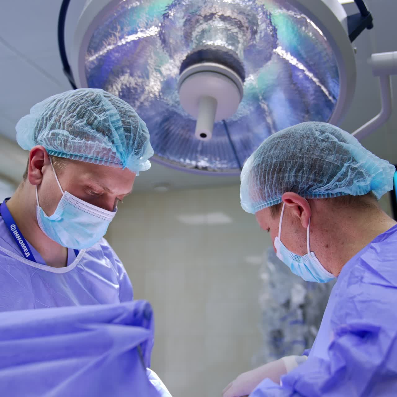 Focused surgeons busy at operation. Cooperating male doctors perform plastic surgery