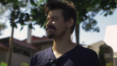 Male-smile-happy-outdoor-park-along-tree-beard-moustache-slow-motion