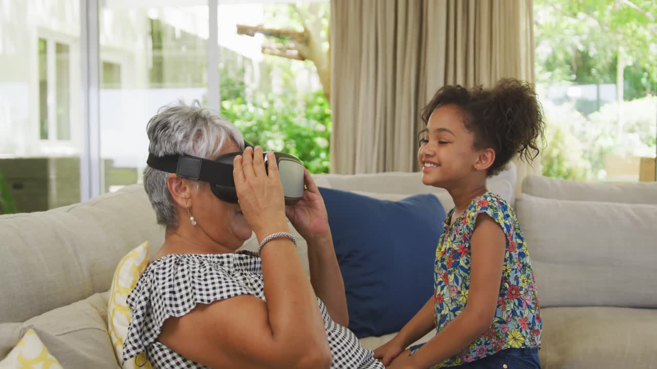 Grandmother and granddaughter using virtual reality headset at home