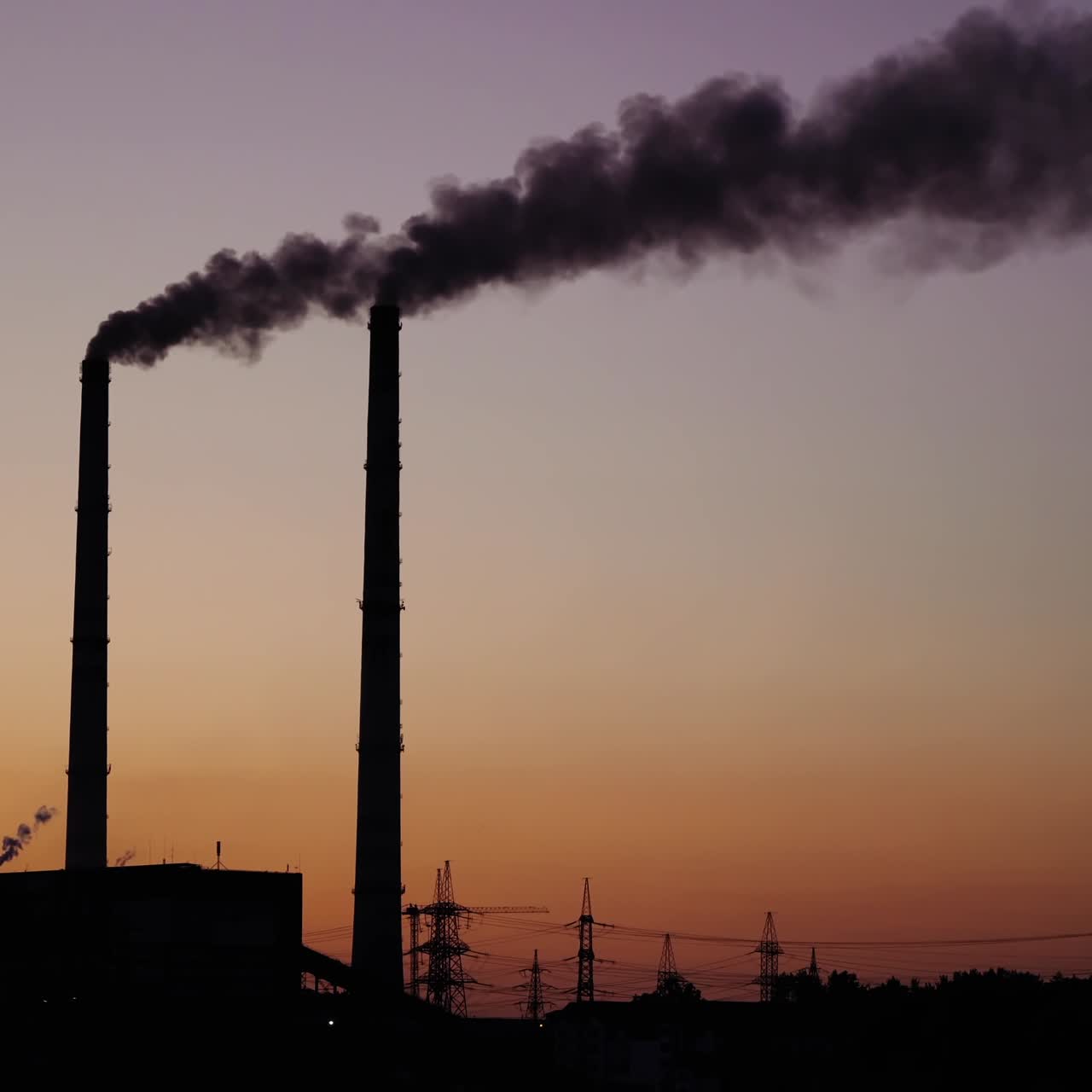 Dark smoke from pipes on the evening sky. Dirty emissions from pipes of industrial plant pollute the environment. Ecological problems.