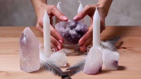 hands arranging amethyst, crystals, and candles for a spiritual ritual