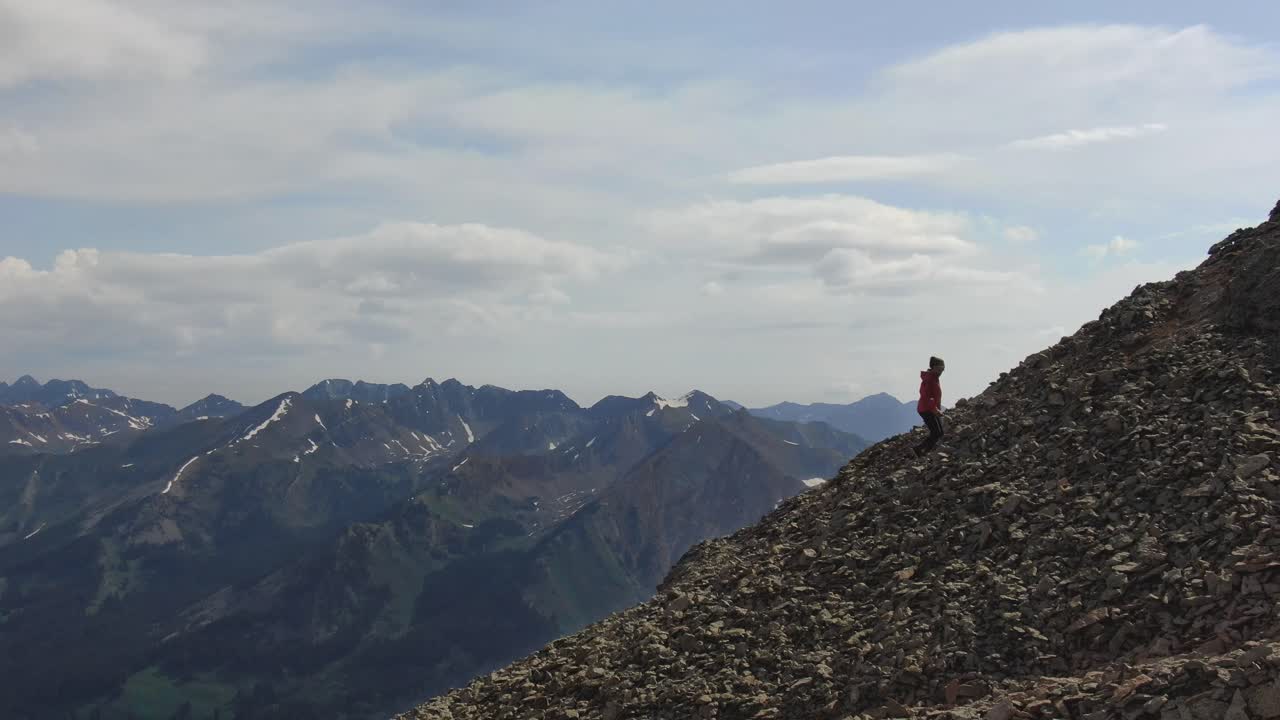 una sola persona escalando la cresta de la montaña con montañas detrás