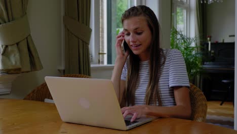 young attractive woman calls while working on a laptop sitting at a table, slow motion