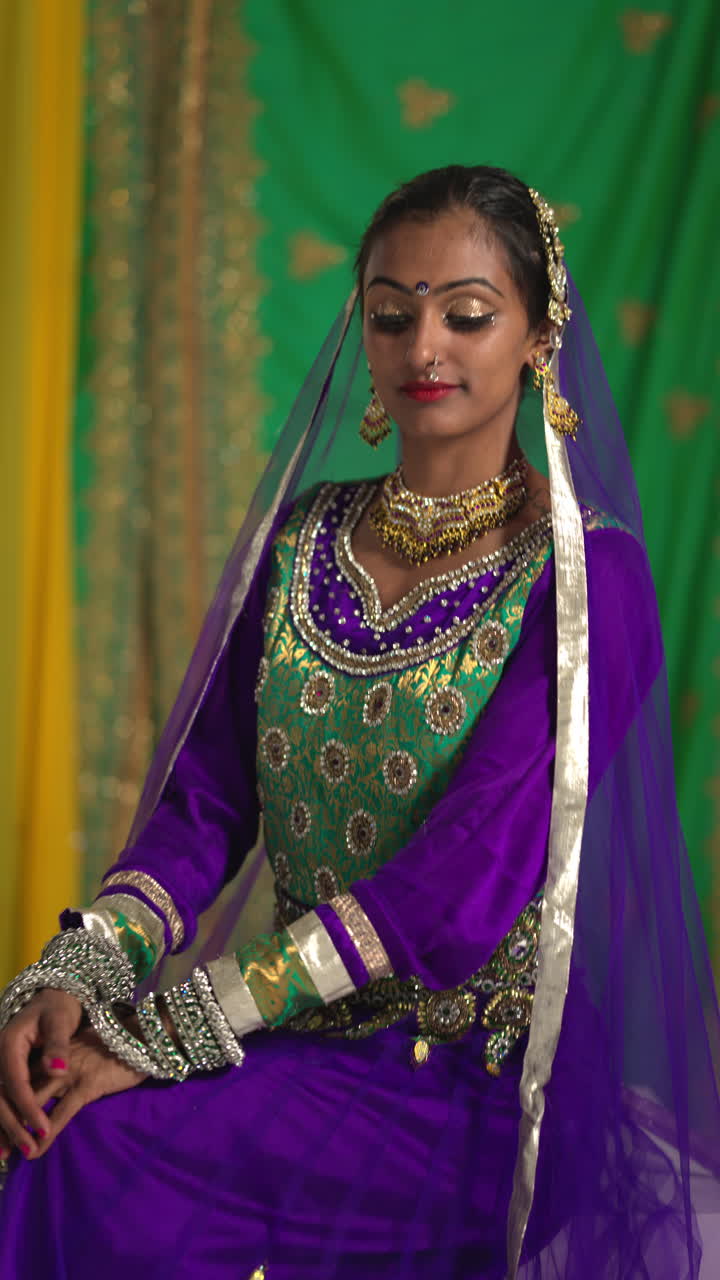 retrato de video vertical de una bailarina de kathak que realiza un baile vestida con el vestido tradicional indio y joyas mirando a la cámara
