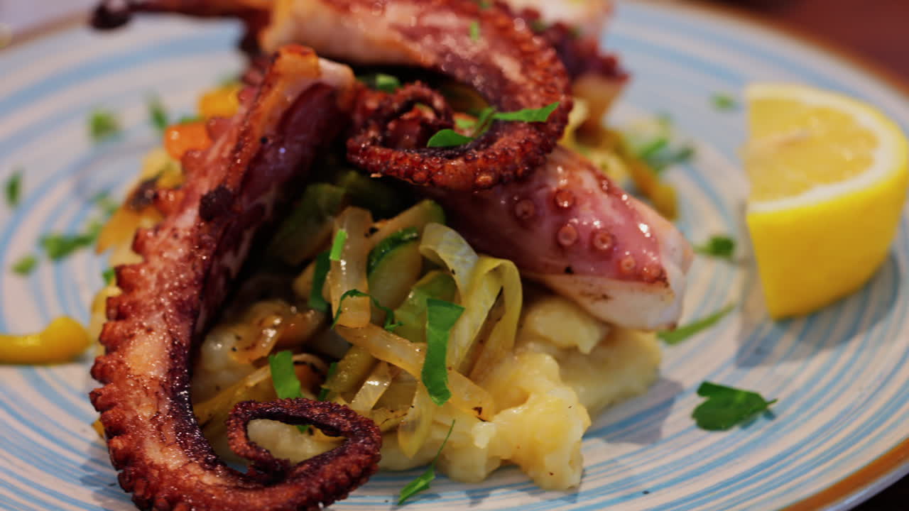 Close up of grilled octopus on a puree and a piece of lemon at a restaurant