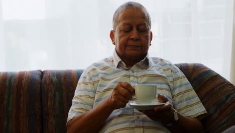 portrait of senior man having coffee on sofa 4k