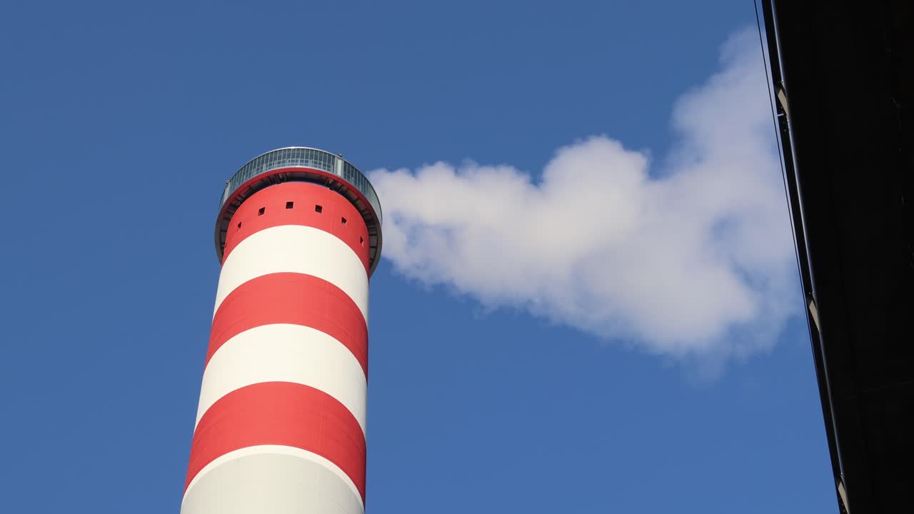 Red and white chimney with thick white smoke, industrial pollution