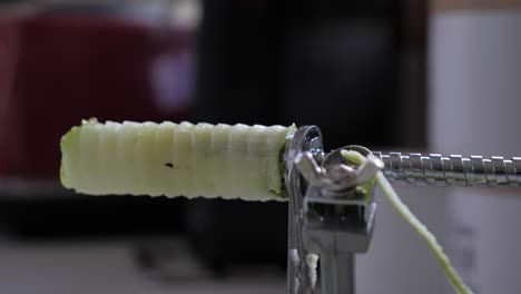 Mans-hand-grabs-at-green-apple-and-pulls-away-from-core-on-silver-metallic-device-on-kitchen-bench