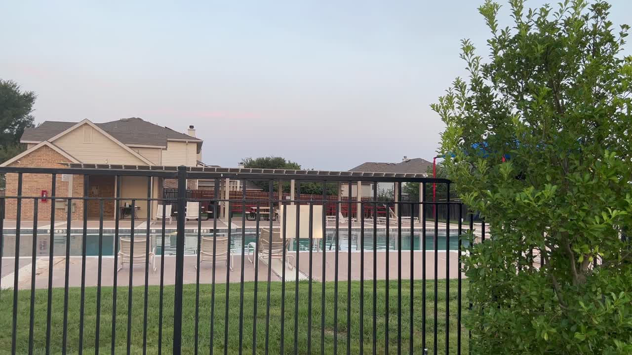 울타리를 통해 볼 수 있는 뜨거운 여름 동안 4k의 교외 지역 커뮤니티 이웃 수영장