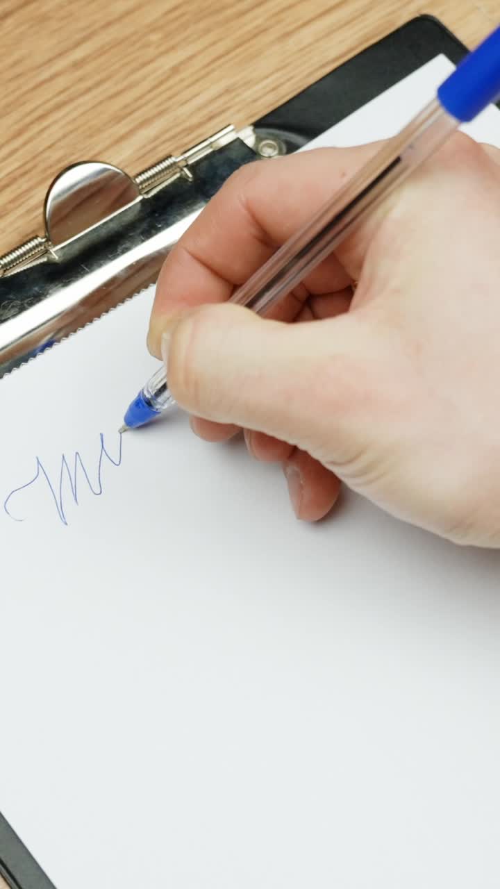 Hand writing on clipboard with blue pen, close-up, clean and focused setting