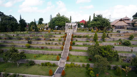 Una-Mujer-Con-Un-Largo-Vestido-Blanco-Sube-Las-Escaleras-Del-Famoso-Palacio-Acuático-De-Ujung-En-Bali,-Indonesia