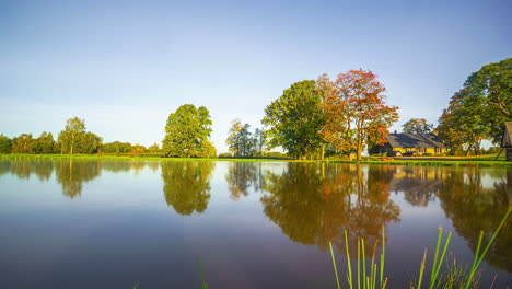 timelapse of a lake and sky with seasons changing from autumn to summer, with trees and a house