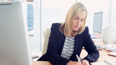 Mujer-De-Negocios-Usando-Computadora-Y-Tomando-Notas