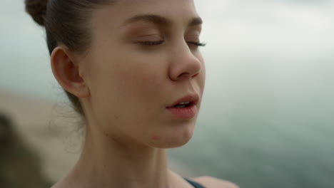 yoga woman breathing calmly meditating on seaside close up. girl closing eyes.