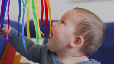 Baby-Spielt-Mit-Regenbogen-Seidenbändern-In-Zeitlupe