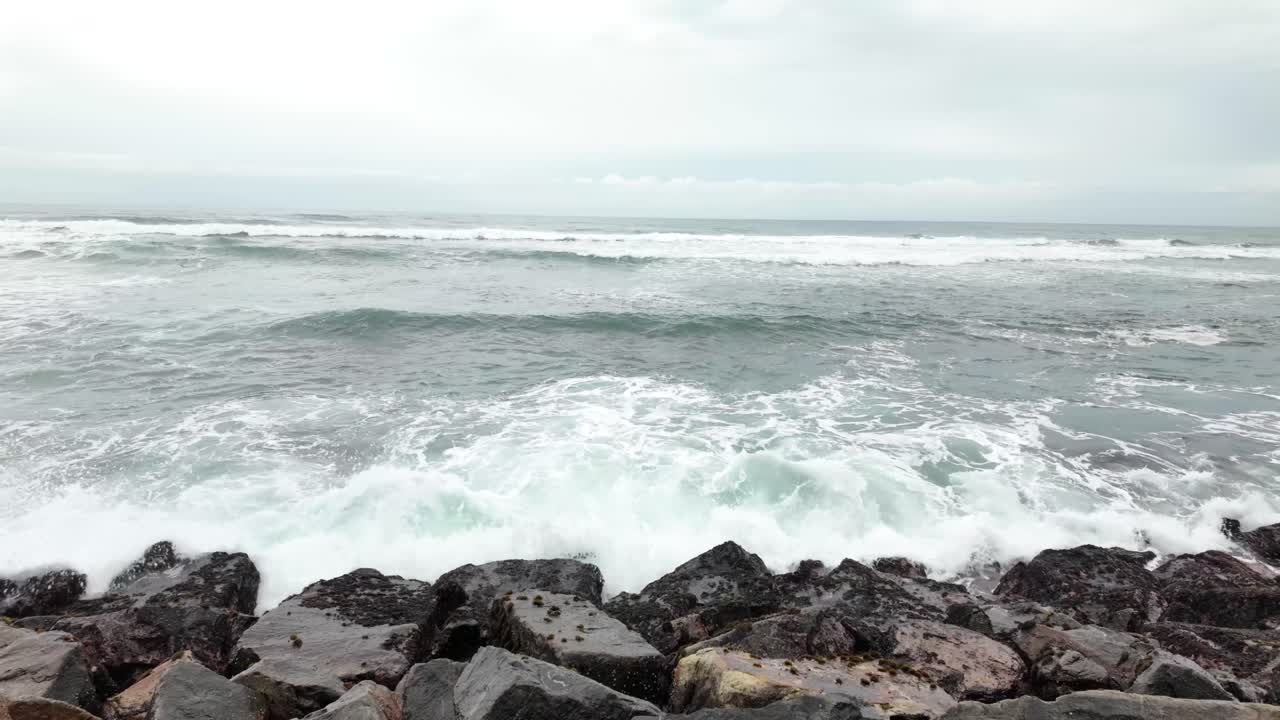 Stormy Indian Ocean waves tide water over giant pebble stones of Sri Lanka shoreline