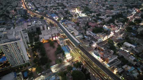 an aerial view of the busy vadapalani signal area of chennai city taken in the evening shows the city's theater, mall, congested streets, apartment buildings, and metro station