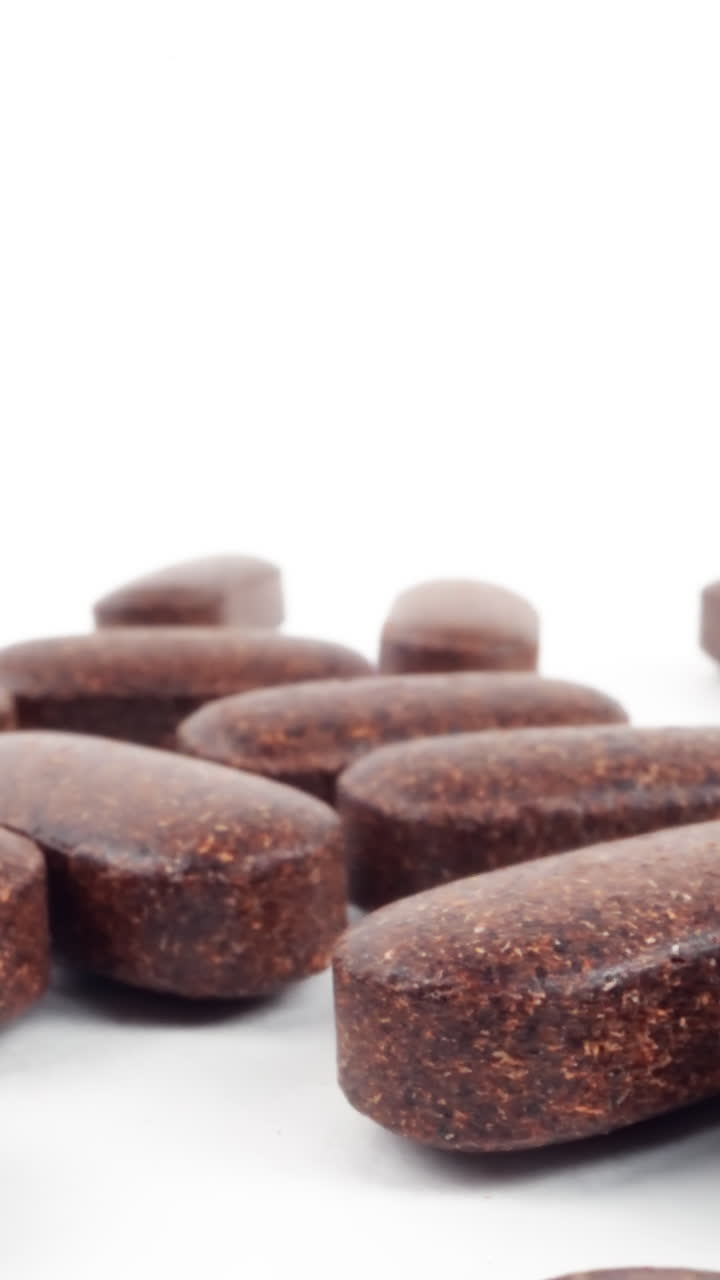 una toma de alta clave de pastillas naturales de hierbas marrones extendidas sobre un fondo blanco brillante