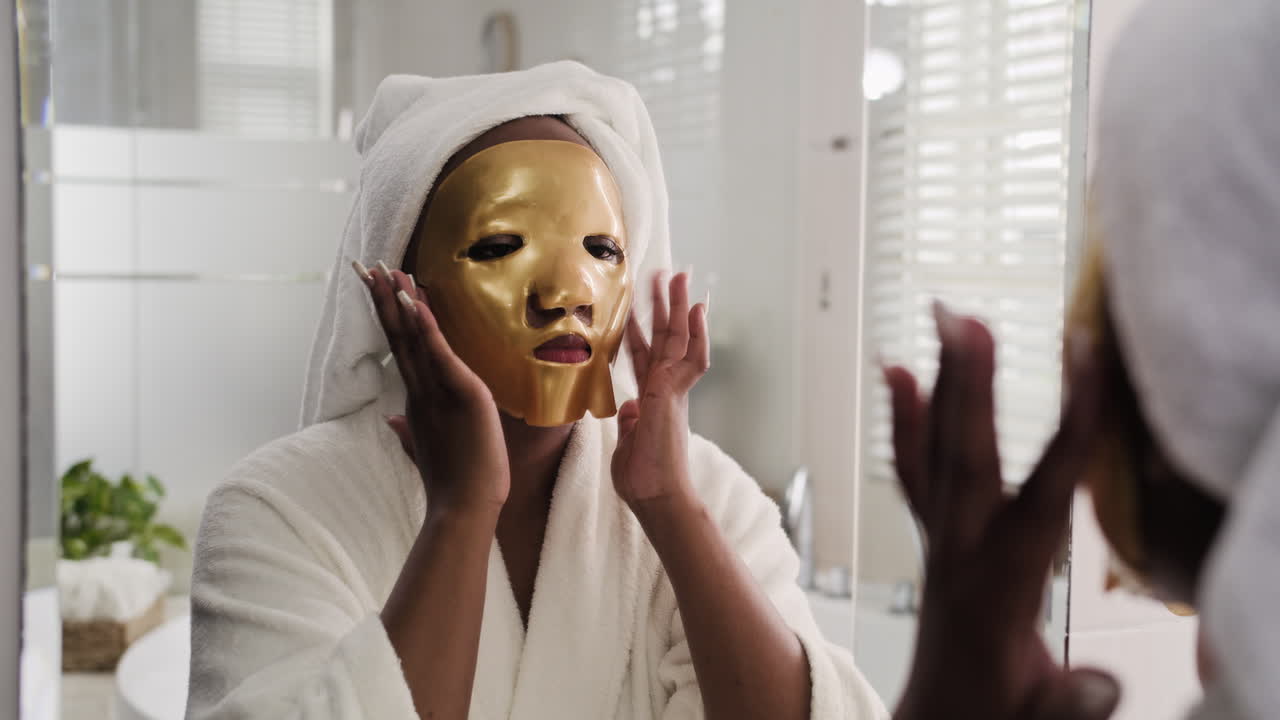 Mulher negra aplicando máscara de hidrogel no rosto no banheiro