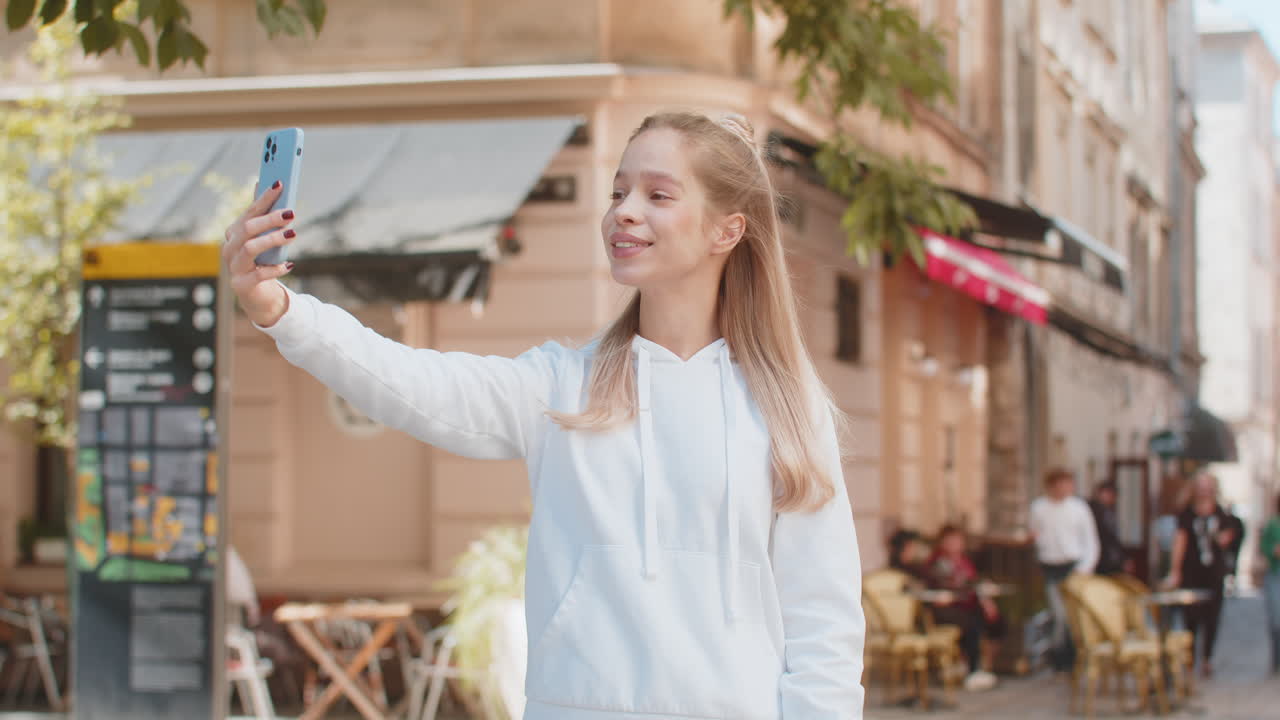 mujer joven caucásica chica turista hablando video chat hablando llamada telefónica teléfono inteligente en la calle de la ciudad