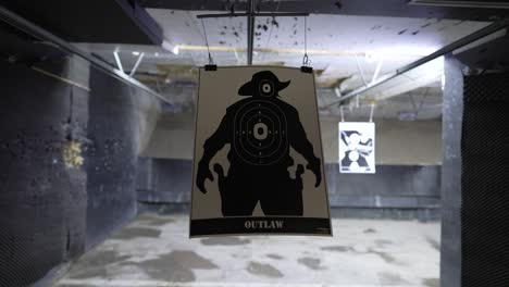 close up moving clip of an unused target moving backwards on a rail to the back of an indoor shooting range