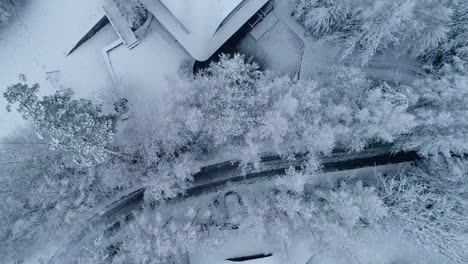 cinematic top-down aerial drone shot of beautiful town entirely covered in snow surrounded by mountains