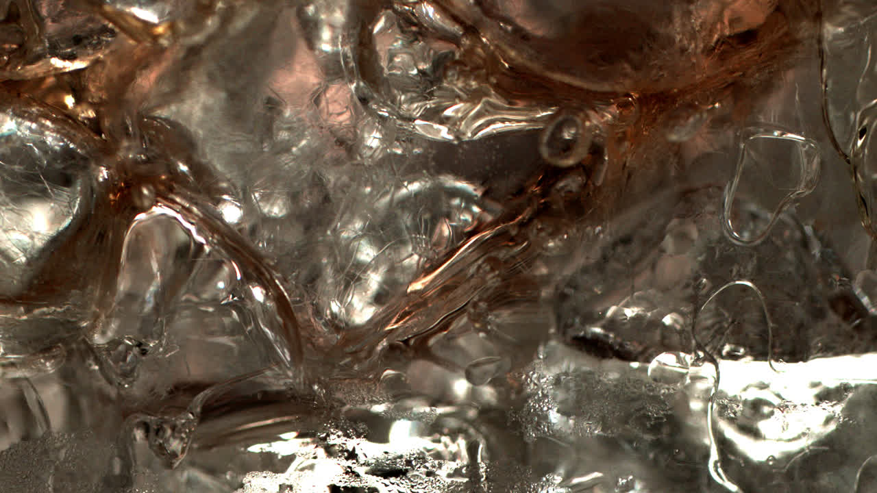 Pouring coke on ice cubes extreme close-up