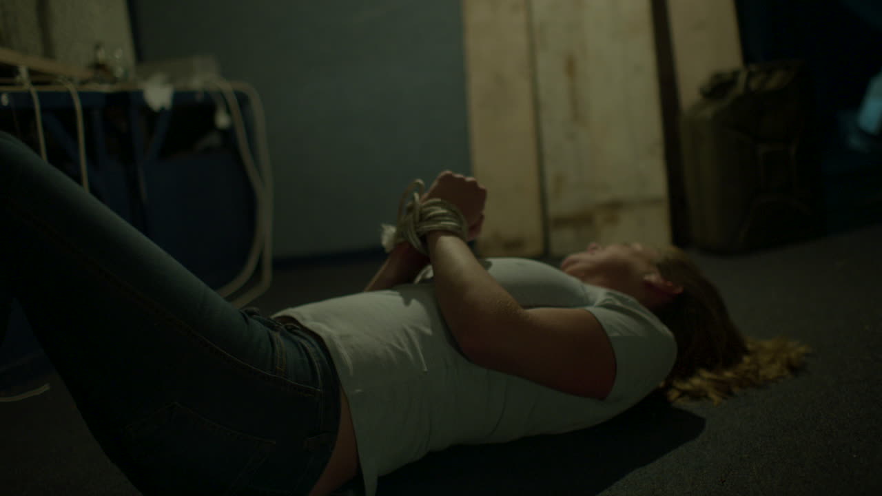 mujer atada en un sótano aterrador tratando de liberarse