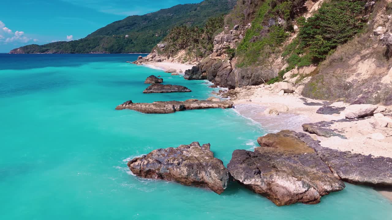 Aerial flying over secluded tropical beach with white sand, turquoise water, and lush green cliffs, Barahona, Dominican Republic