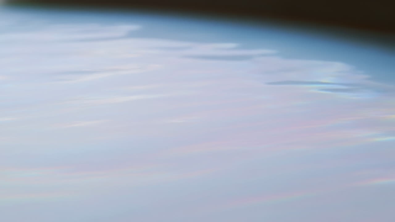 Nuages doux aux couleurs pastel au-dessus du limbe terrestre vus depuis l'orbite terrestre basse, atmosphère calme, fine brume bleue, irisée