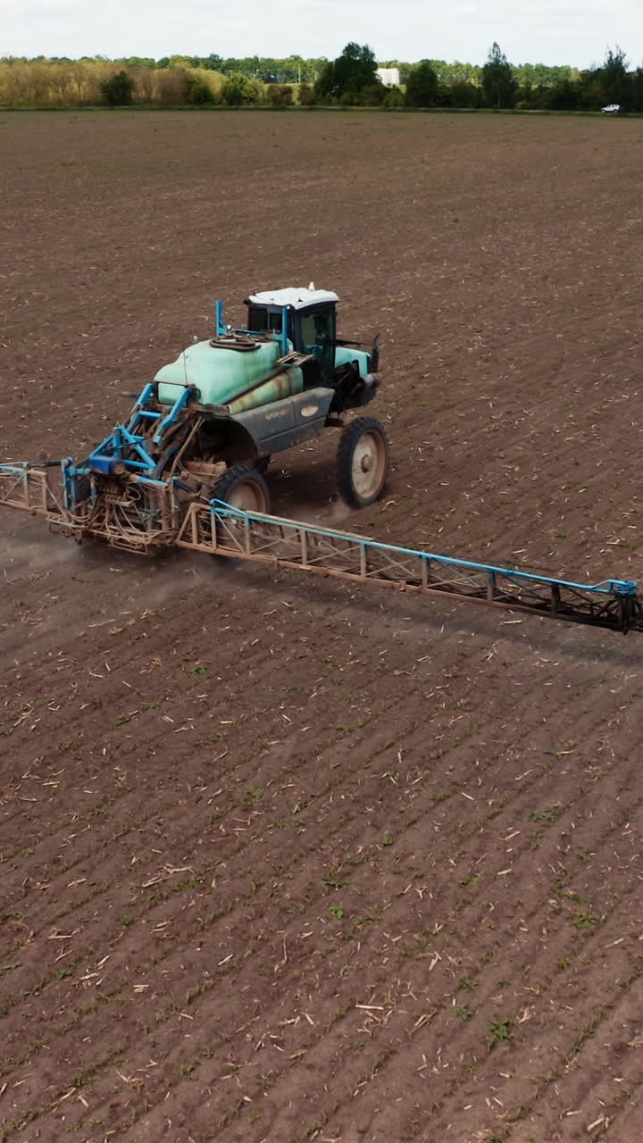 Tractor spraying field with fertilizer. Tractor spraying chemical pesticides with sprayer on the large agricultural field