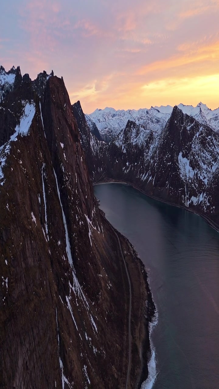 Tramonto su montagne innevate e baia tranquilla in Norvegia. Ideale per promozioni turistiche o documentari naturalistici.