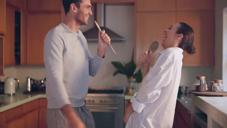 cantando, jugando o una pareja feliz en la cocina del hogar