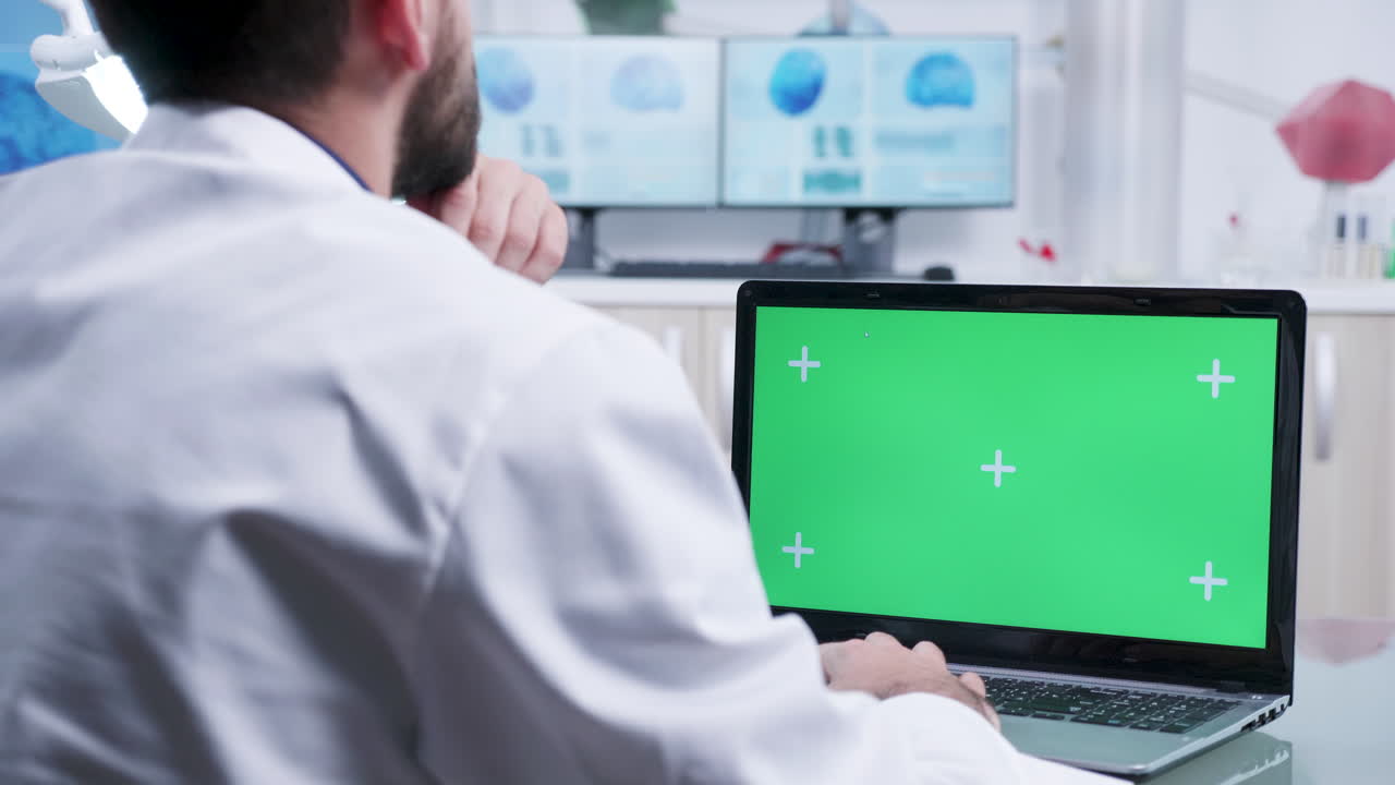 Doctor using laptop with green screen in lab