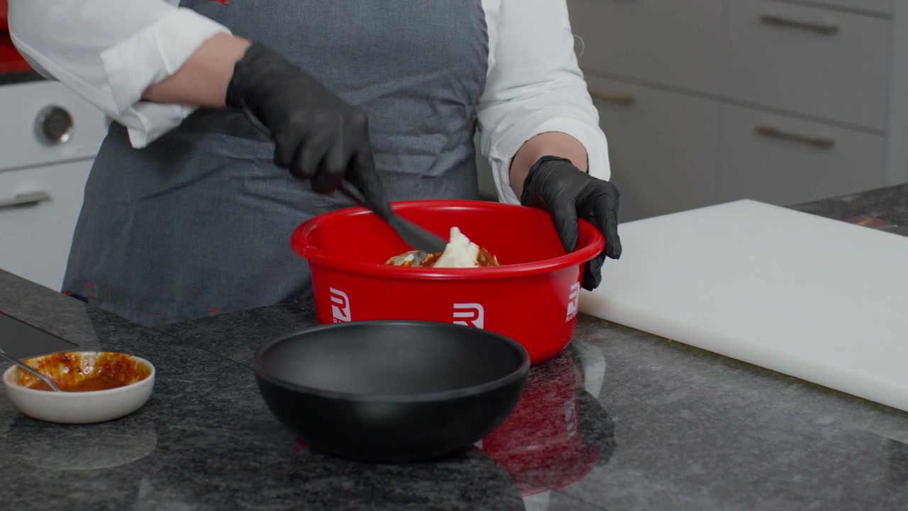 Food service worker preparing ingredients in a commercial kitchen environment. Close-up footage suitable for catering, food production, hospitality, meal preparation, and hygiene themes